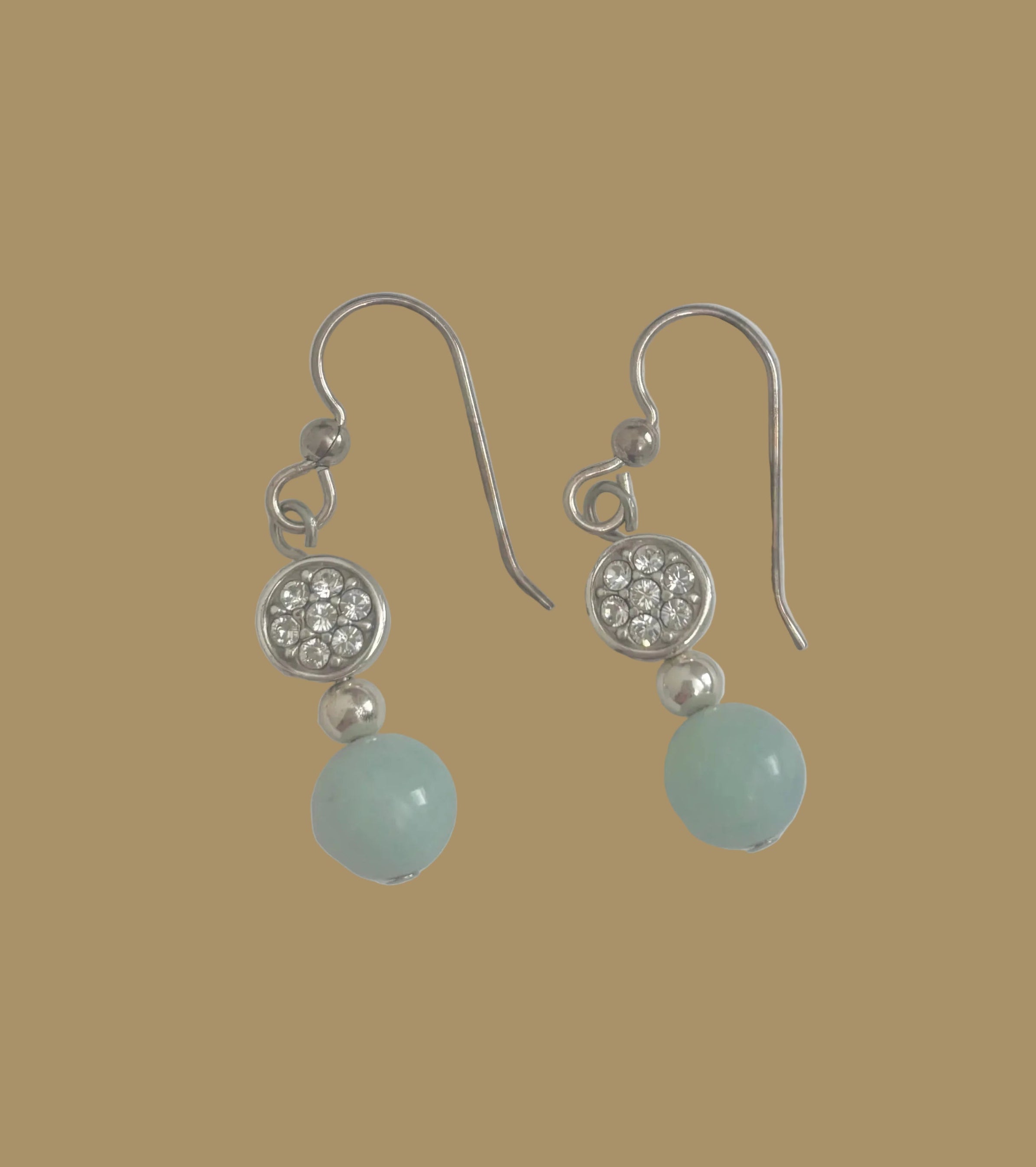 Pair of earrings with green beads and silver accents on a light gray background
